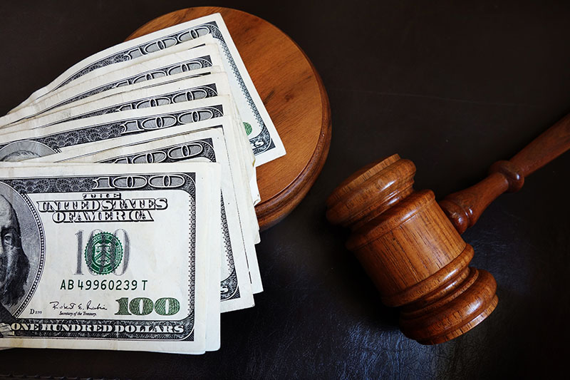 money legally paid to child support, some hundred dollar bills laid across a gavel