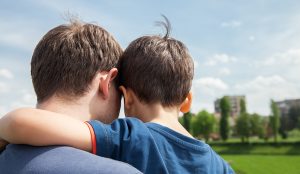 Father with custody of son on a city background. View from the back