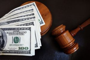 money legally paid to child support, some hundred dollar bills laid across a gavel
